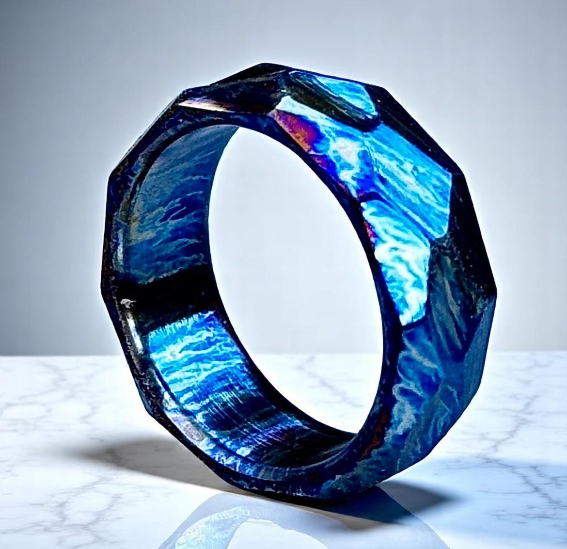 Blue and black geometric ring on a marble surface with a gray background