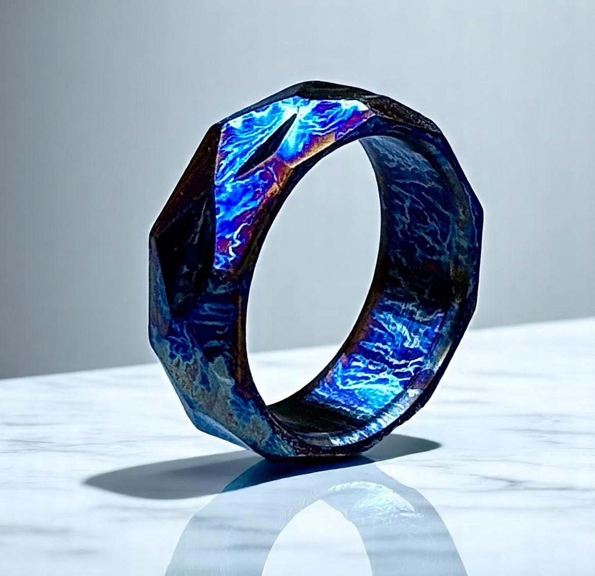 Novelty ring with blue and purple iridescent design on a reflective surface