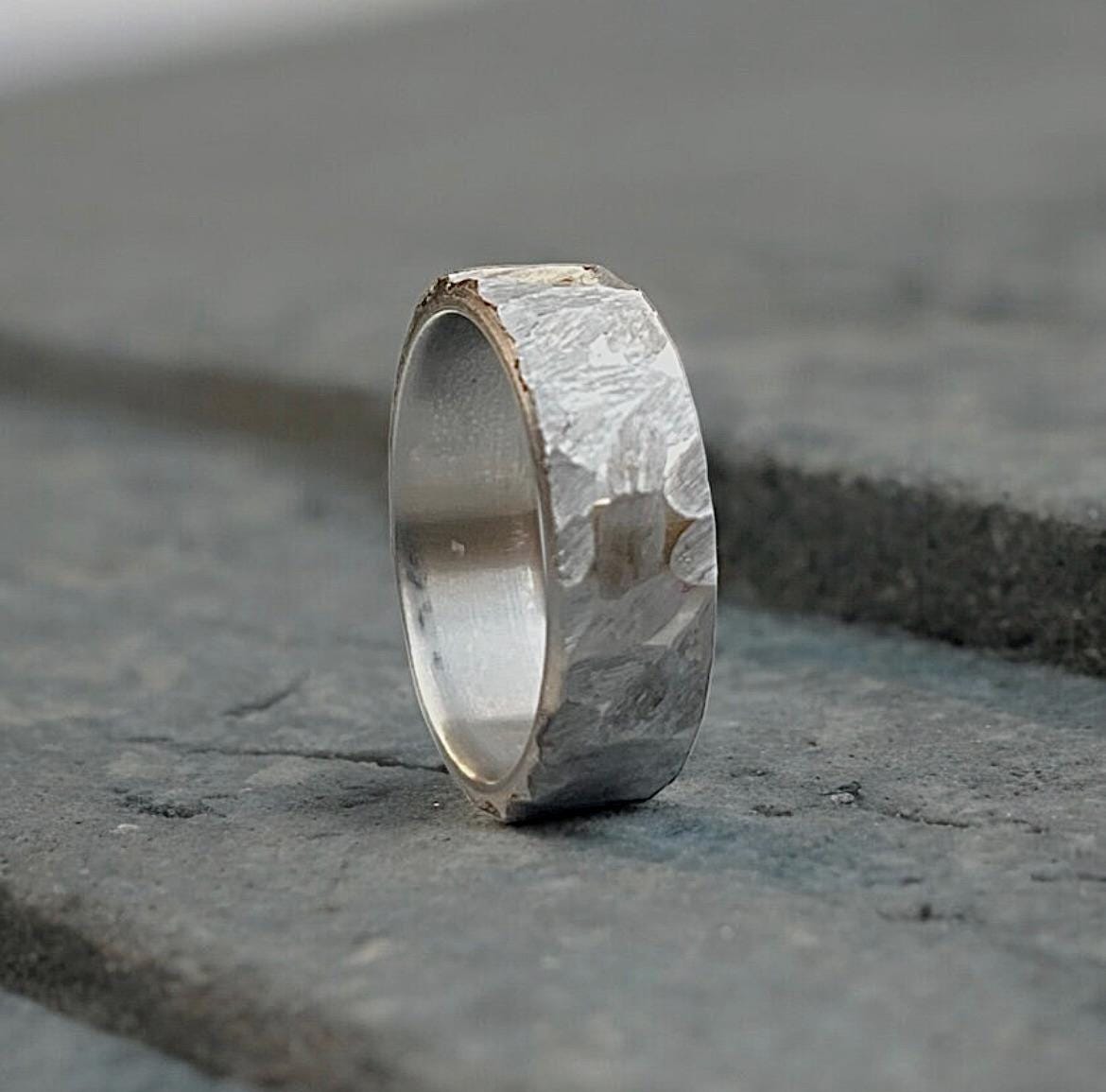 Silver ring with a textured surface on a stone surface