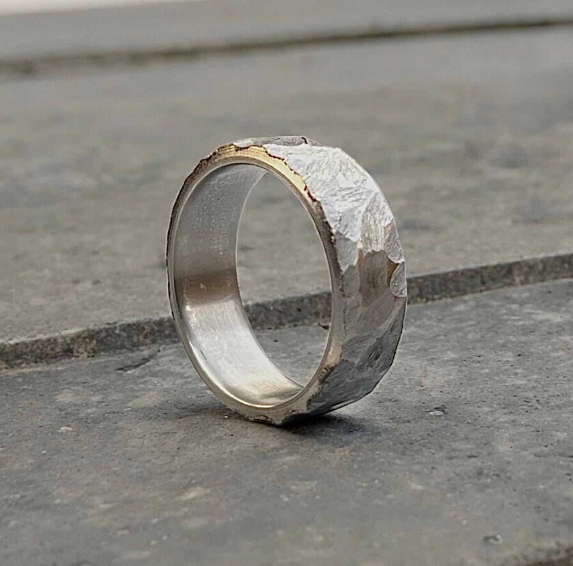 Silver ring with a rough, industrial finish on a concrete surface