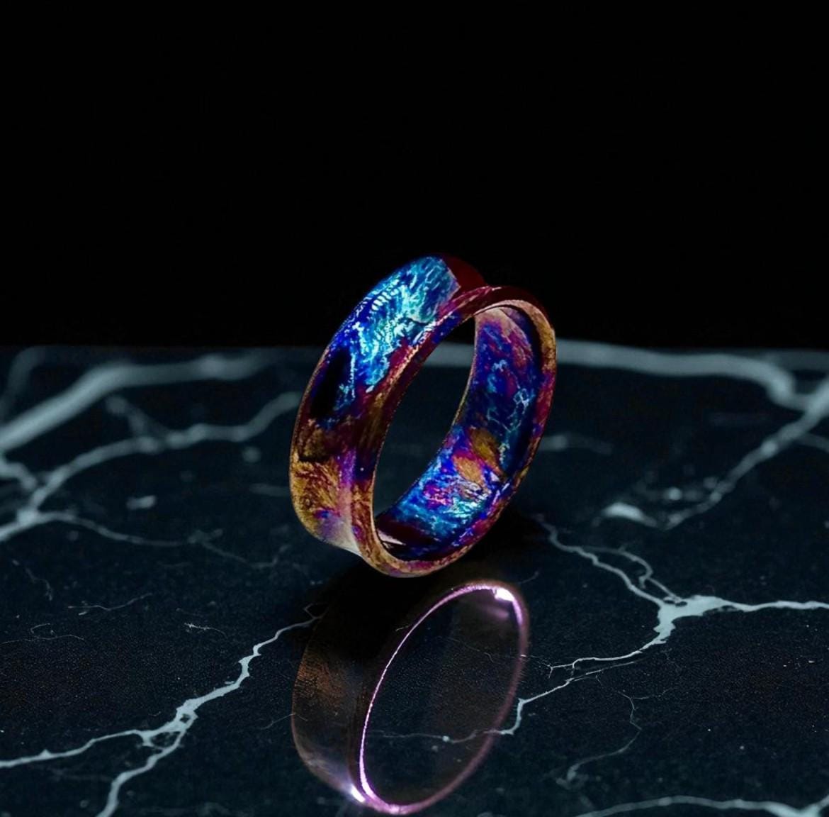 Colorful ring with a metallic sheen on a black marble surface