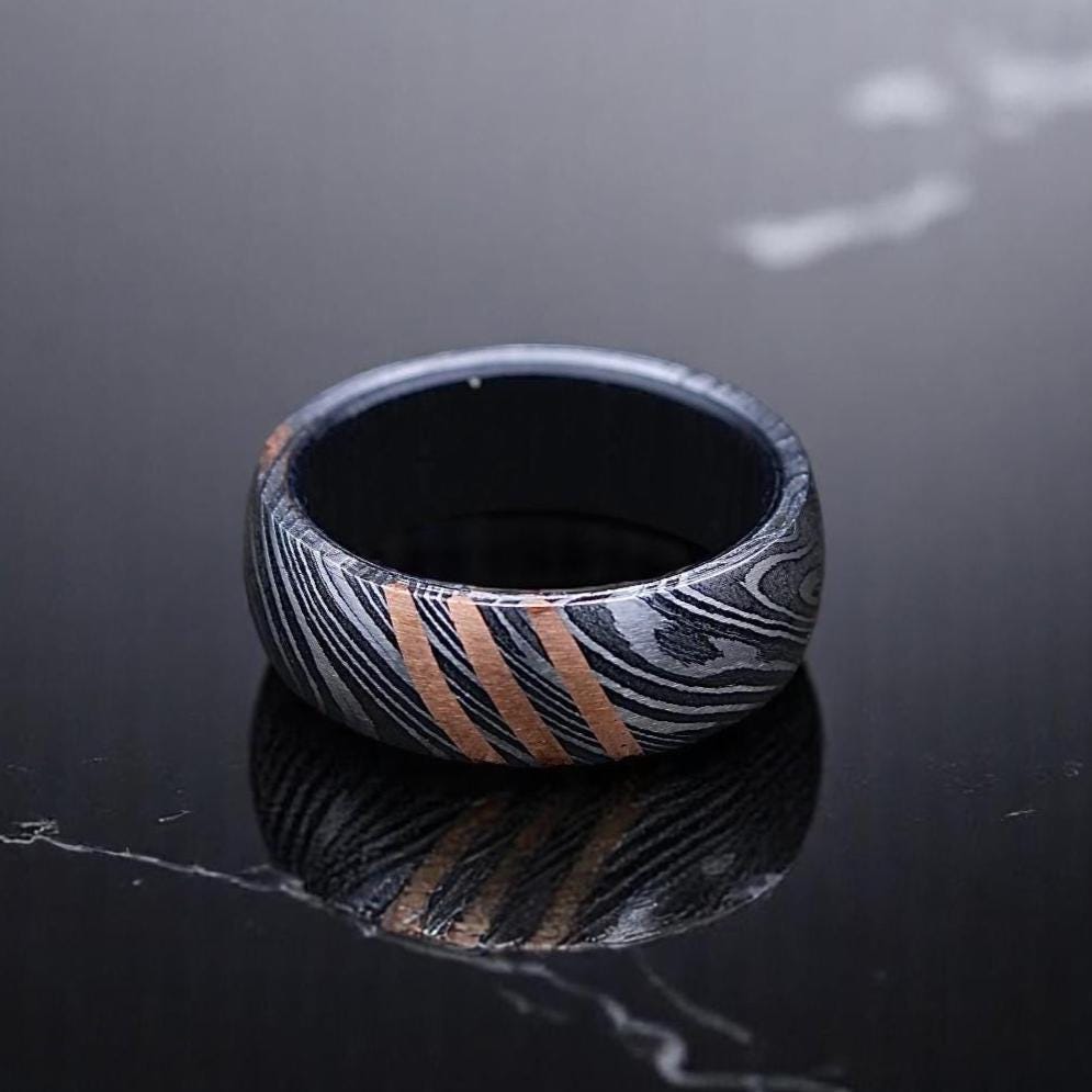 Black and silver patterned ring on a dark surface