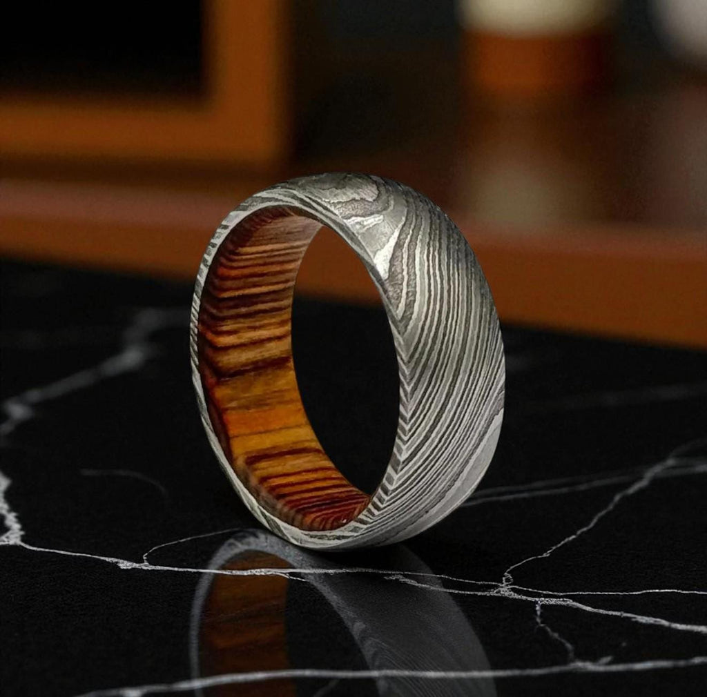 Wooden and metal ring on a reflective surface with a blurred background